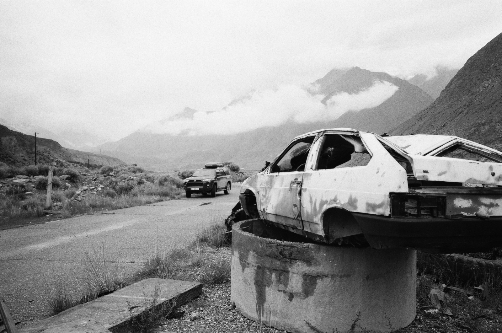 black and white abandoned car on a mountain road