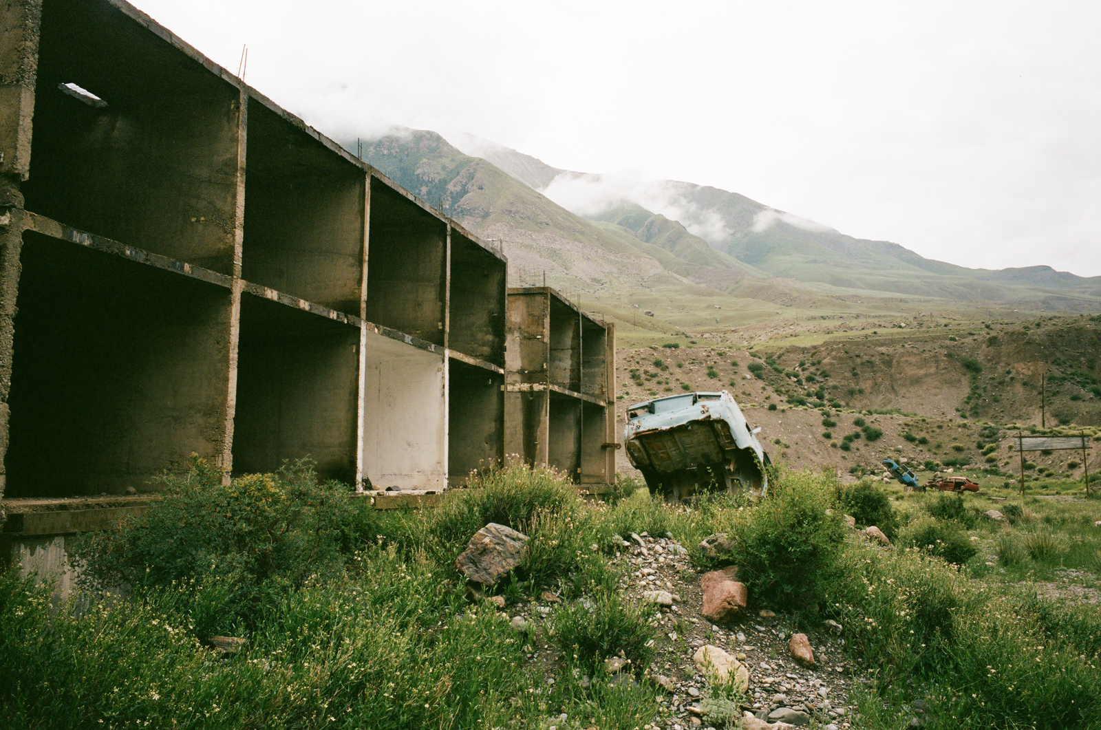 concrete roadside structure beneath clouded mountains