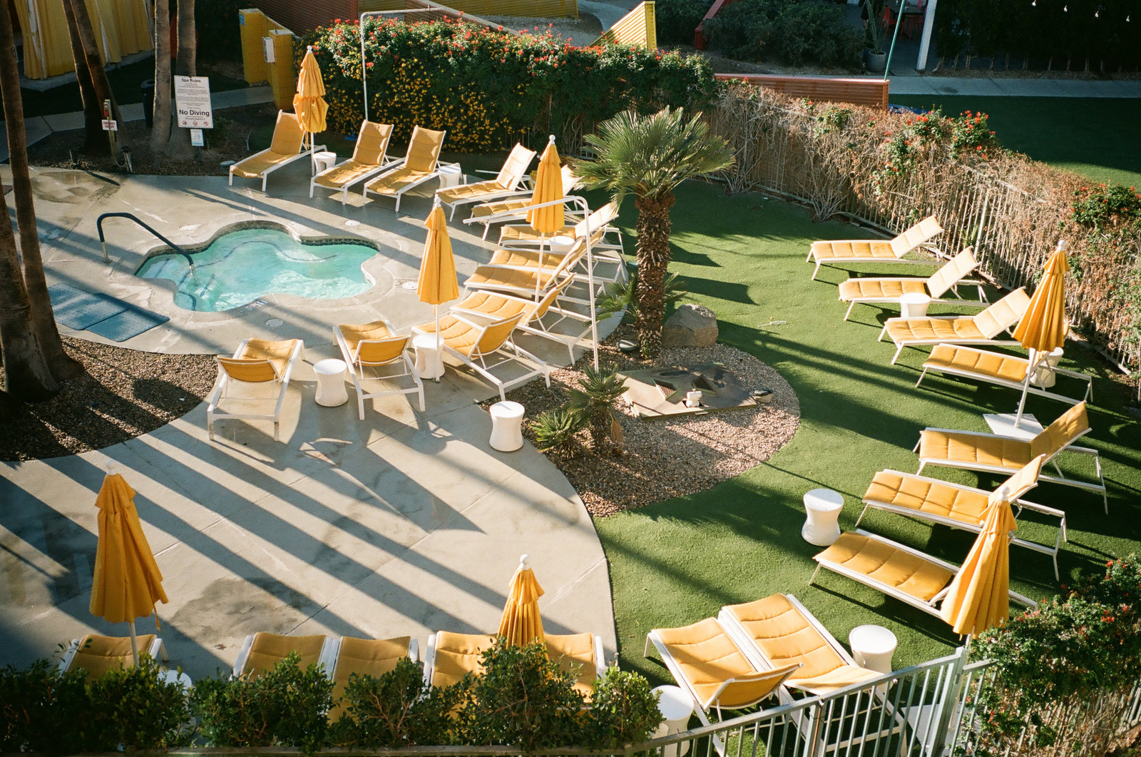 sunlit hotel pool with yellow umbrellas